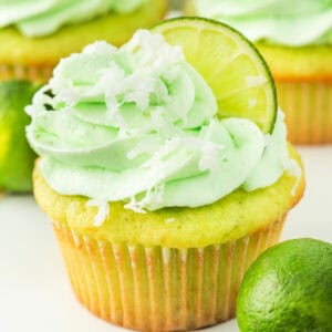 Bright and fluffy coconut lime cupcake with green frosting, lime slice, and shredded coconut on top