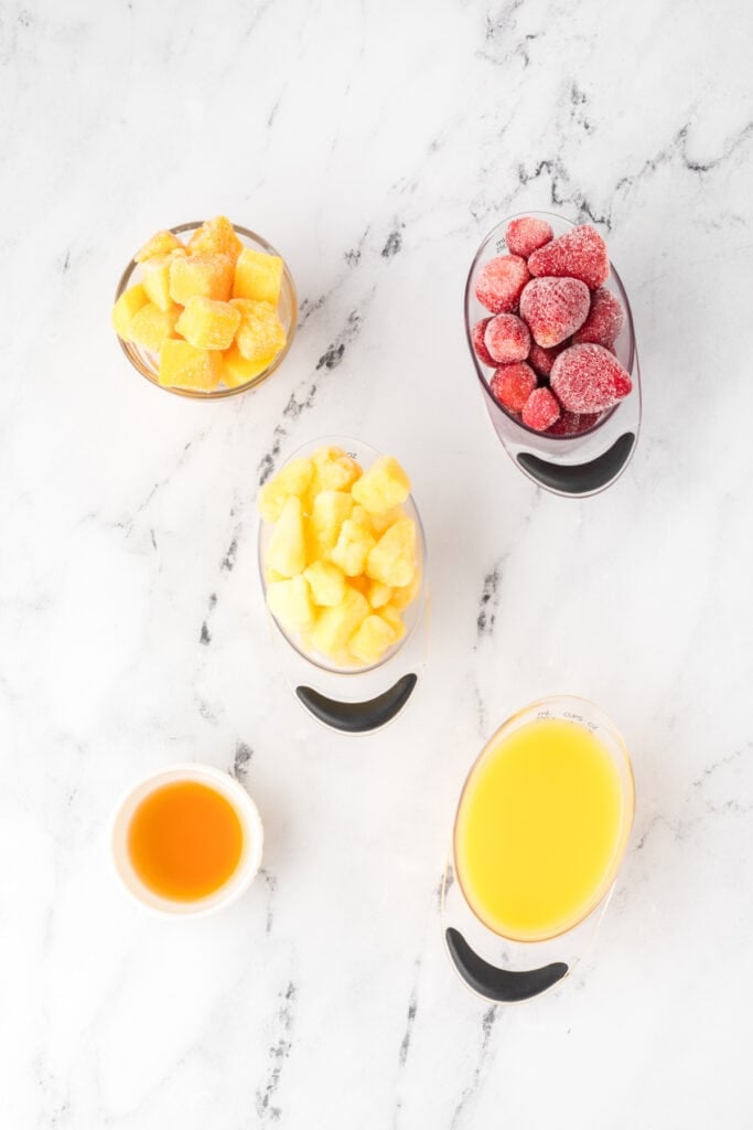 Measured ingredients for sunrise sunset smoothie on a marble background.
