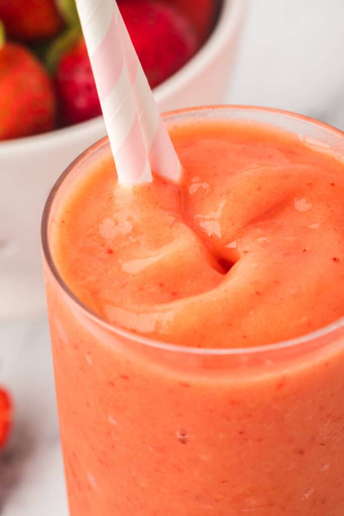Close-up of sunrise sunset smoothie with striped straw.