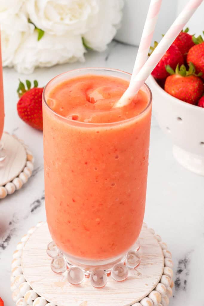 Single glass of sunrise sunset smoothie served on a decorative coaster.