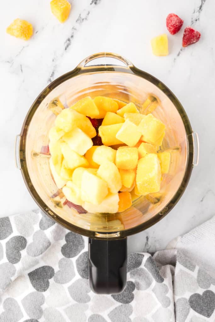 Frozen fruit and orange juice added to blender for sunrise sunset smoothie.