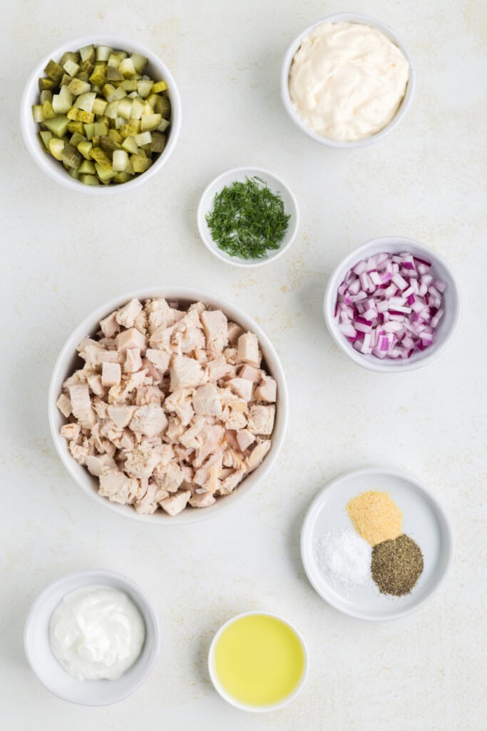Overhead view of all ingredients in small bowls for dill pickle chicken salad.