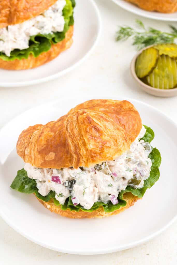 Closeup of dill pickle chicken salad served on a croissant with lettuce.