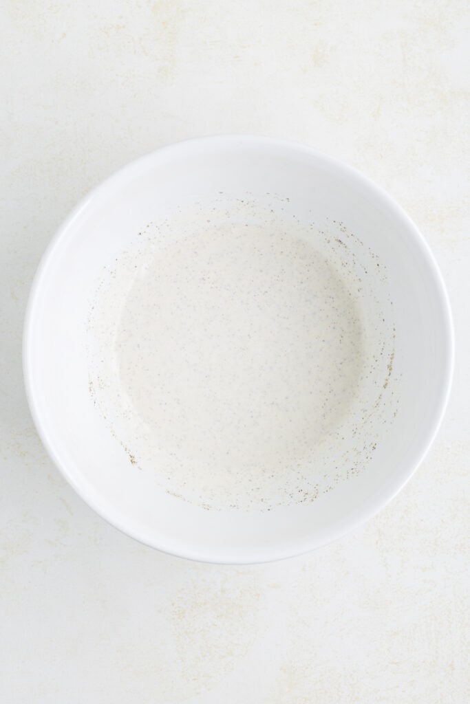 Whisked creamy dill pickle dressing in a white mixing bowl.