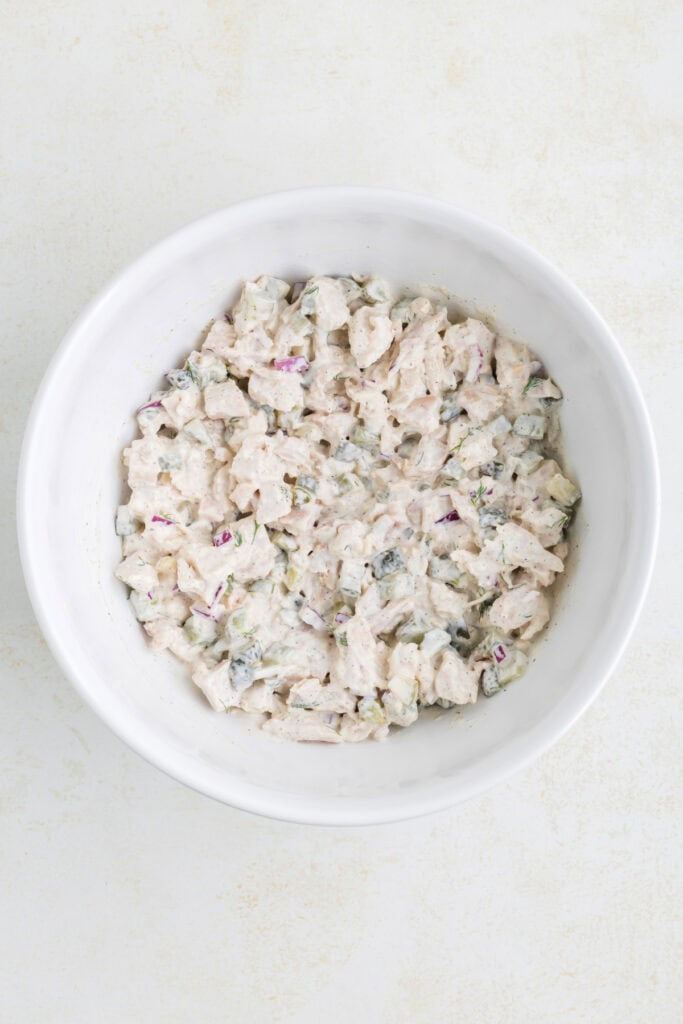 Fully mixed dill pickle chicken salad in a white bowl.