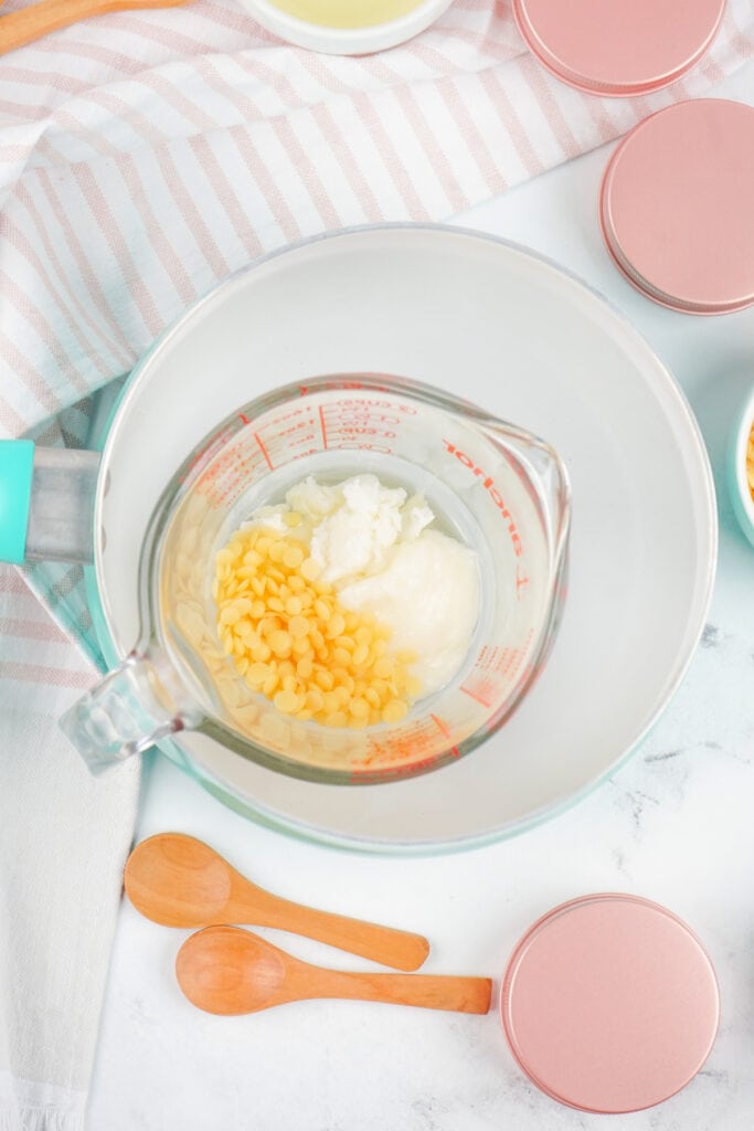 Measuring cup placed in a saucepan with ingredients melting for the dog paw balm.