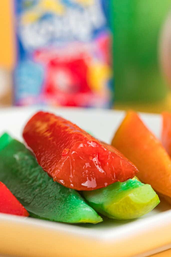 Close-up of brightly colored Kool-Aid pickles arranged on a white plate.
