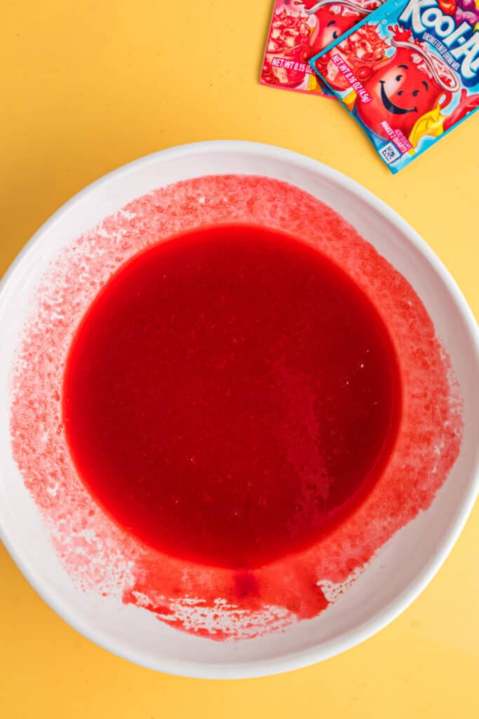 Bright red Kool-Aid mixture fully combined in a white bowl.