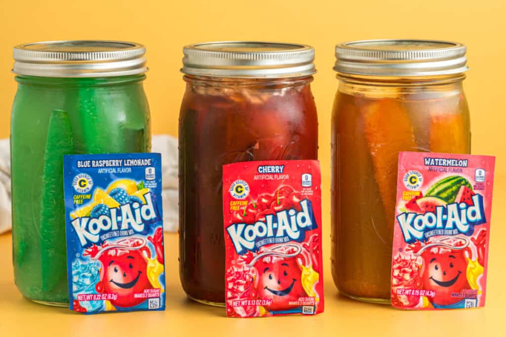 Three jars of Kool-Aid pickles with Blue Raspberry, Cherry, and Watermelon flavors.