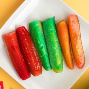 Square image of colorful Kool-Aid pickles arranged neatly on a white plate.