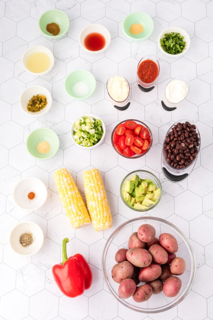 Overhead shot of Southwest Potato Salad ingredients arranged on a white tile background.