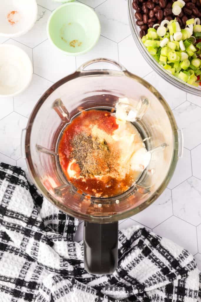 Blender filled with salad dressing ingredients before blending.