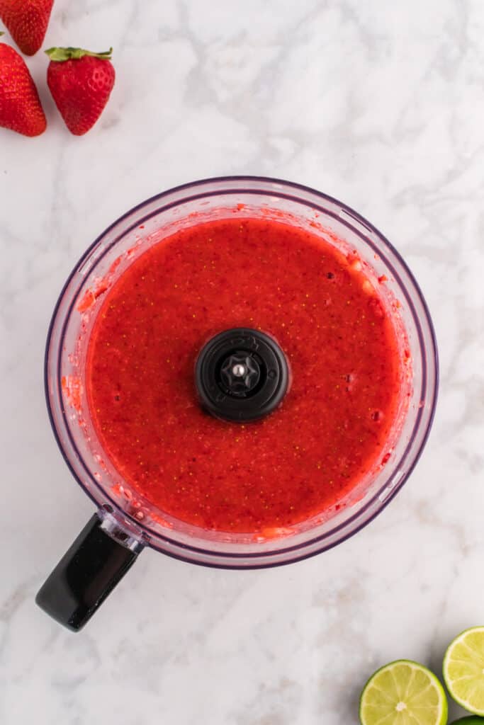 Blended strawberry purée in a food processor, smooth and vibrant red.