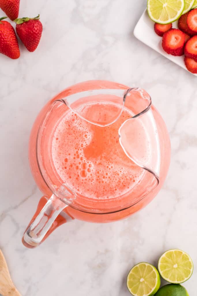 Finished strawberry limeade mixture in a pitcher, light pink and frothy.