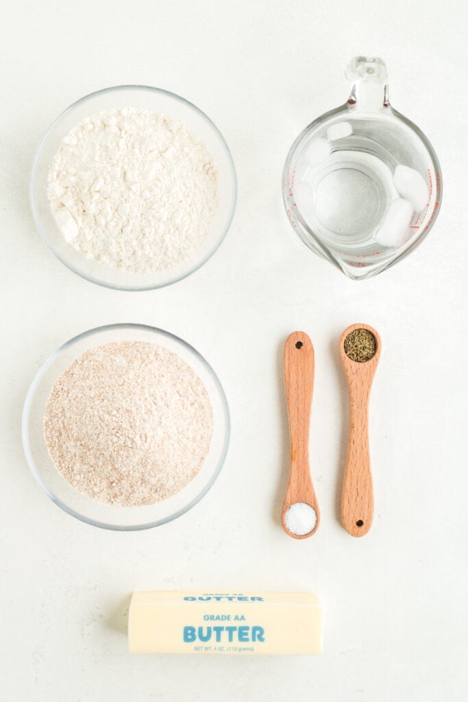 Overhead view of ingredients for galette crust including flours, butter, spices, and iced water.