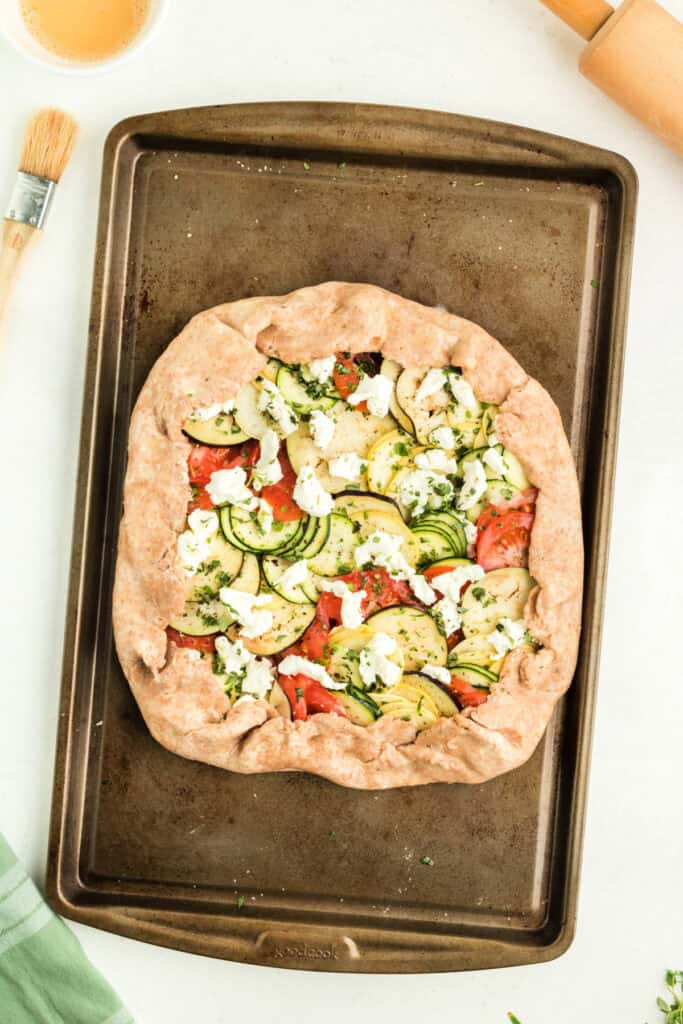 Unbaked summer vegetable galette with folded crust edges, ready to go into the oven.