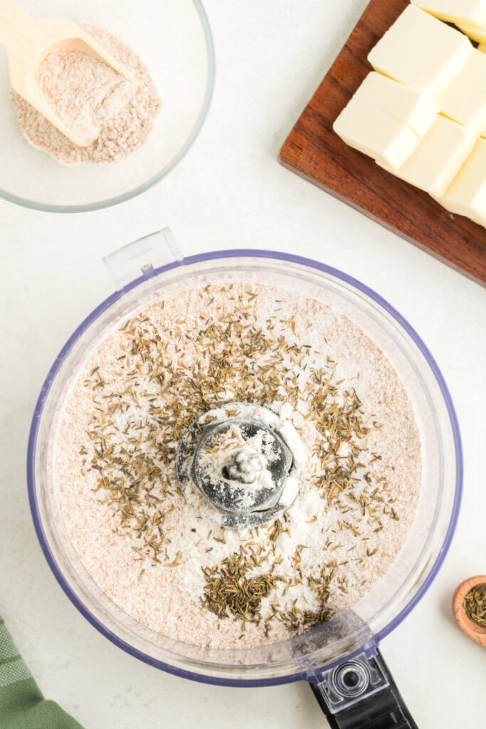 Food processor filled with flour and dried thyme ready to make galette crust.