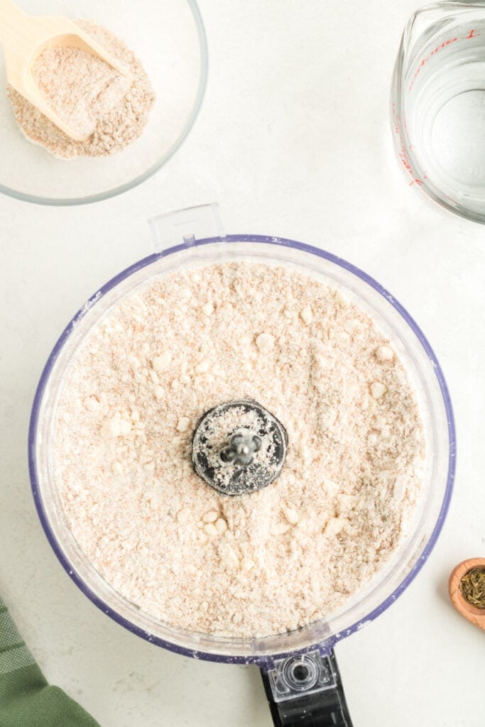 Food processor showing flour and butter mixed into coarse crumbs for galette dough.