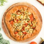 Overhead view of summer vegetable galette on parchment-lined wooden board, ready to serve.