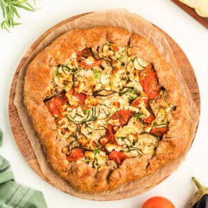 Overhead view of summer vegetable galette on parchment-lined wooden board, ready to serve.