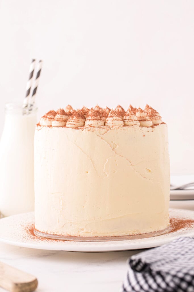 Finished tiramisu cake with smooth frosting and decorative piped tops dusted with cocoa powder.