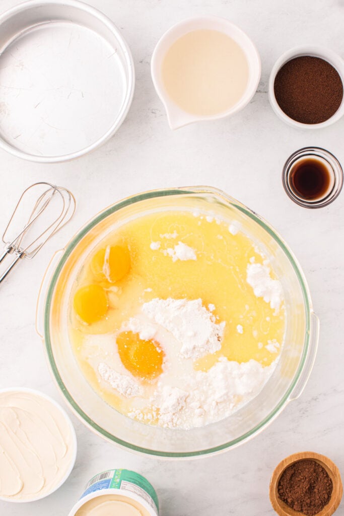 Bowl with eggs, melted butter, and cake mix ready for mixing.