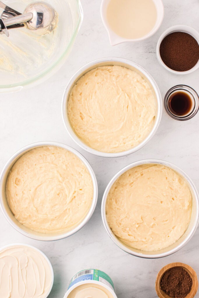 Three cake pans filled with smooth cake batter, ready to bake.