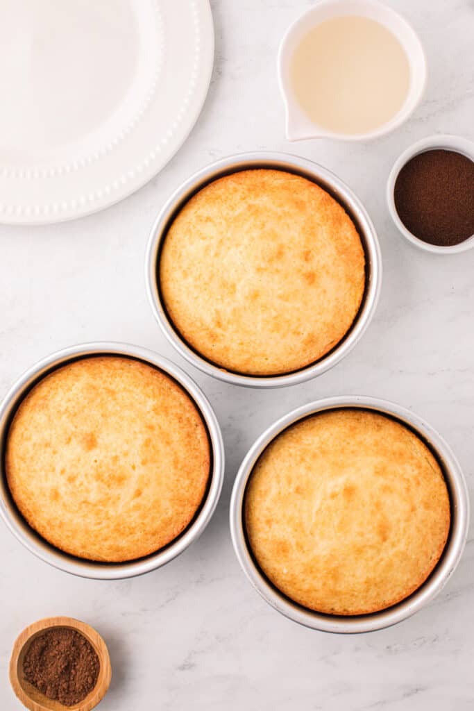 Freshly baked cake layers cooling in their pans.