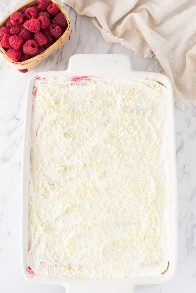 Fully assembled tiramisu topped with grated white chocolate, ready to chill.