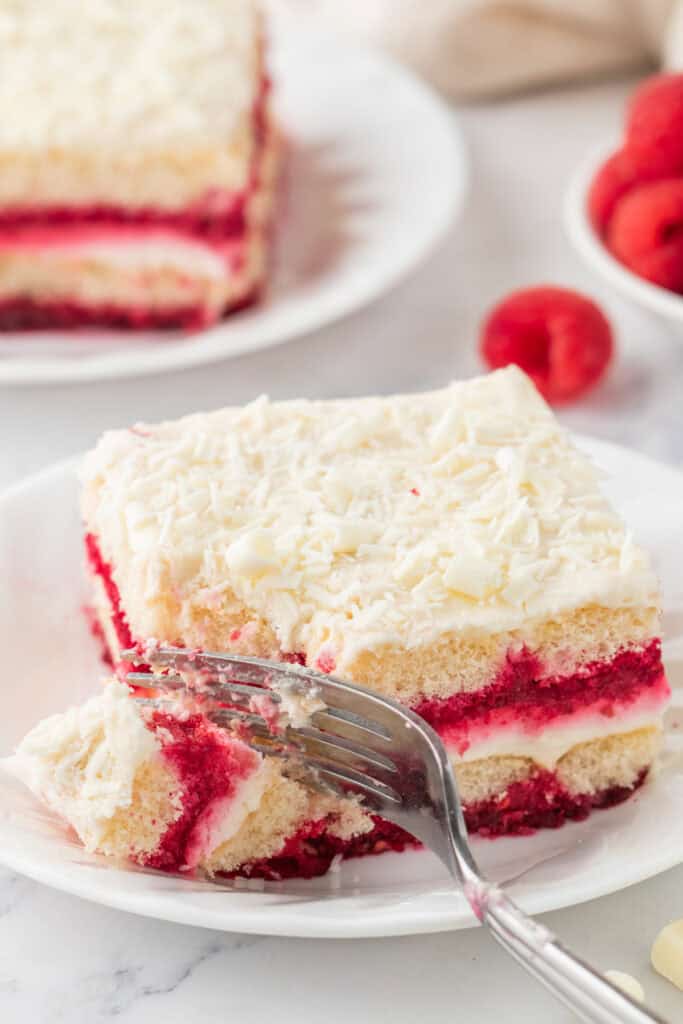 Slice of White Chocolate Raspberry Tiramisu on a plate with a forkful taken out.