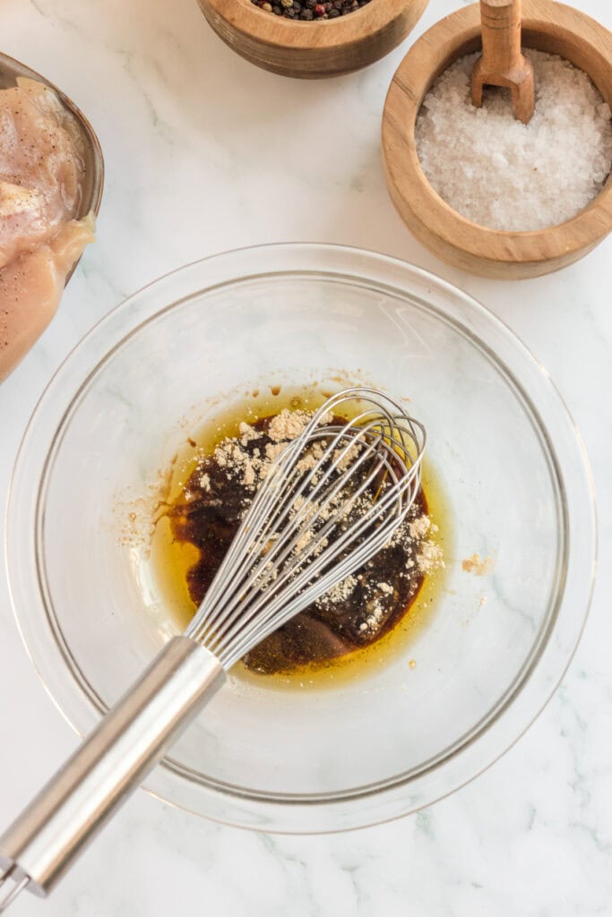 Bowl with balsamic vinegar, olive oil, and dry spices being whisked together