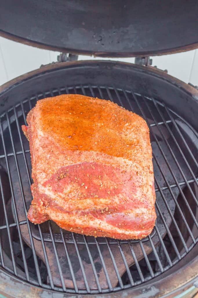 Boston butt placed fat side up on a grill, ready for low and slow cooking.
