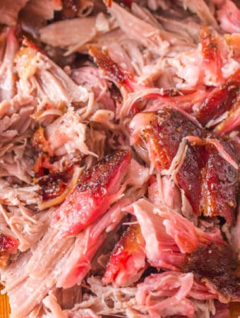 Square crop of juicy shredded pulled pork with visible bark and smoke ring.