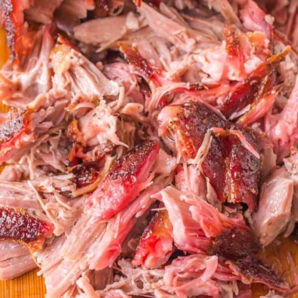 Square crop of juicy shredded pulled pork with visible bark and smoke ring.