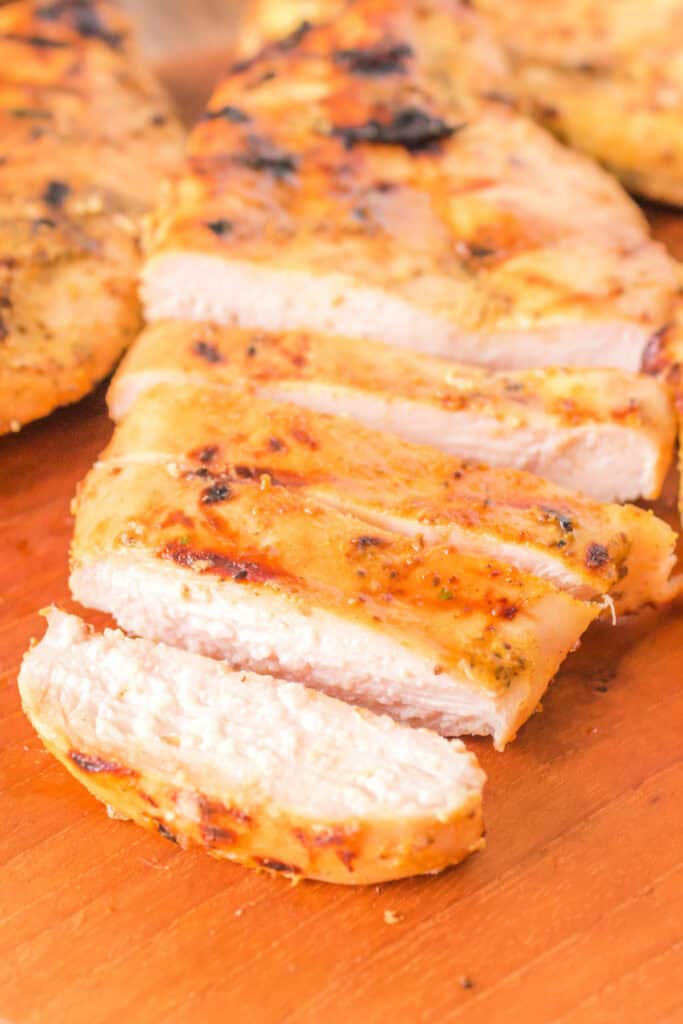 Close-up of juicy sliced honey mustard chicken breast on a wooden board