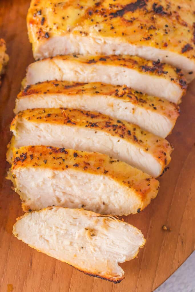 Close-up of juicy sliced lemon pepper chicken breast showing grill marks and tender texture.