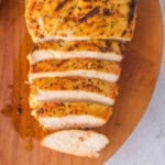 Overhead view of sliced grilled lemon pepper chicken breast on a wooden board.