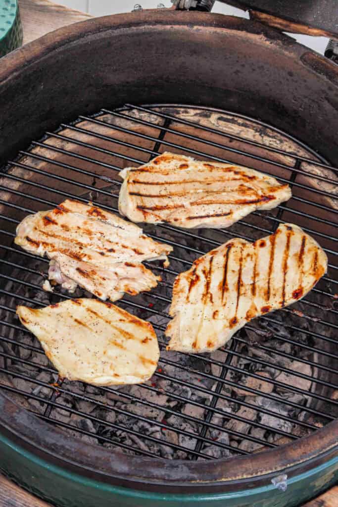 Chicken breasts halfway grilled with visible grill marks