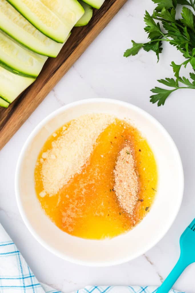 A bowl with melted butter, grated parmesan, and Italian breadcrumbs ready to be mixed.