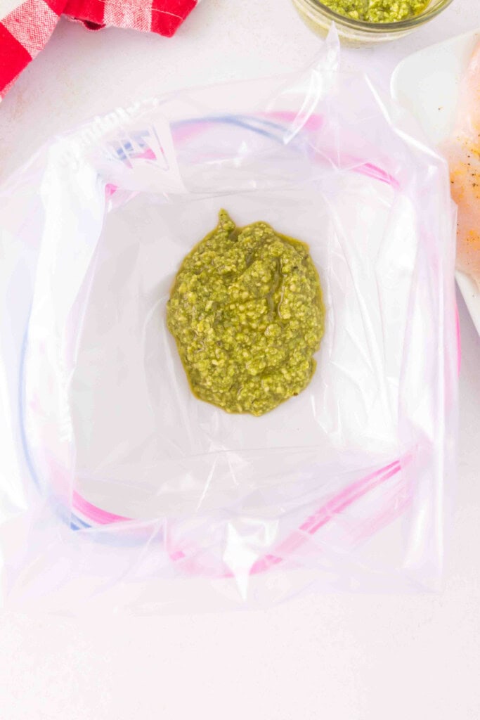 Dollop of basil pesto inside an open zip-top bag ready for marinating.