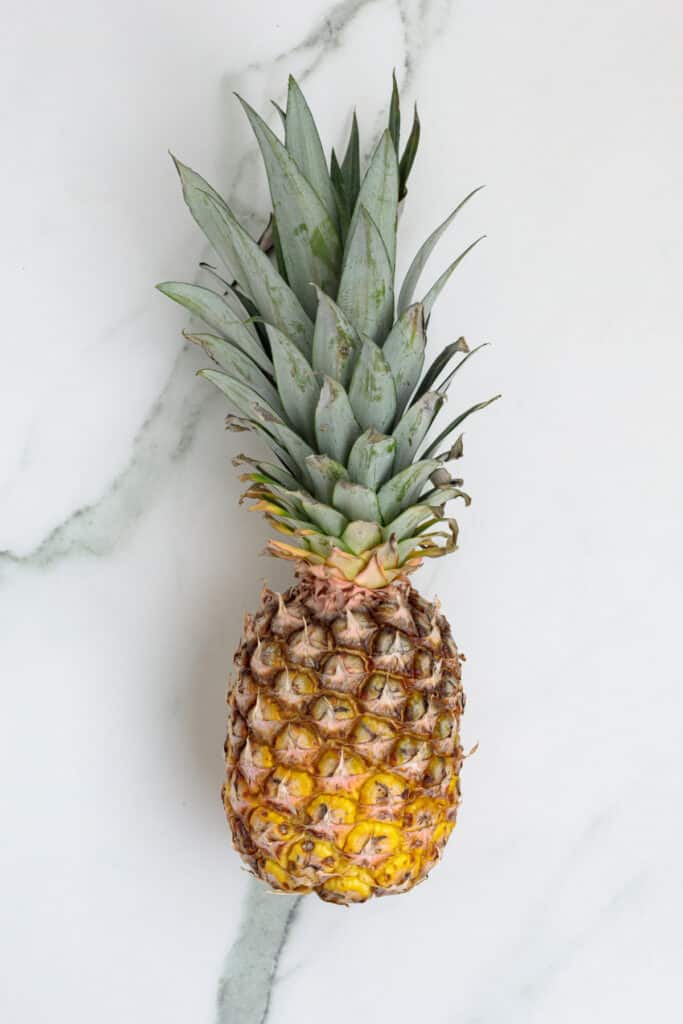 Whole fresh pineapple on a white marble surface
