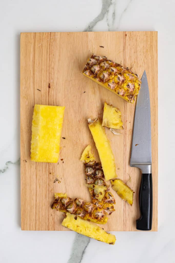 Pineapple pieces with peel and core removed, ready for slicing