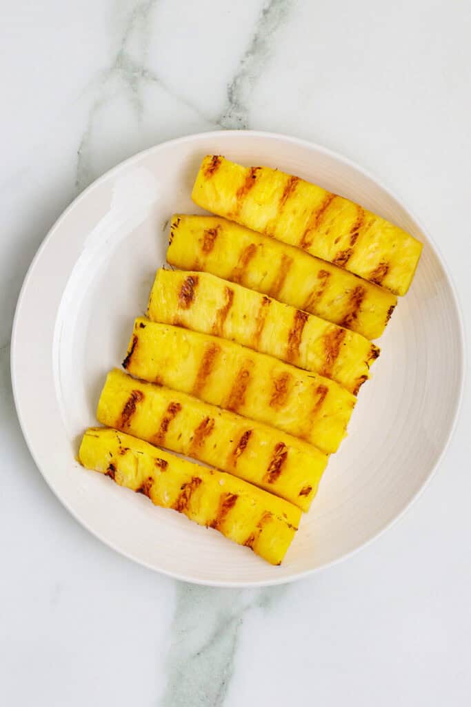 Grilled pineapple spears arranged on a white plate