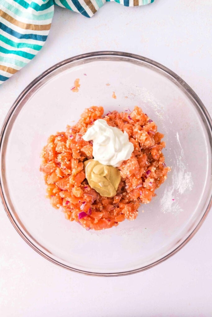Partially mixed salmon burger mixture with sour cream and mustard added on top