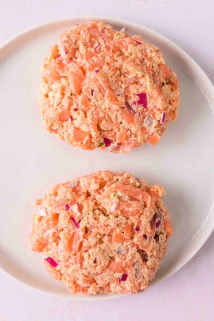 Formed raw salmon burger patties on a plate, ready for grilling