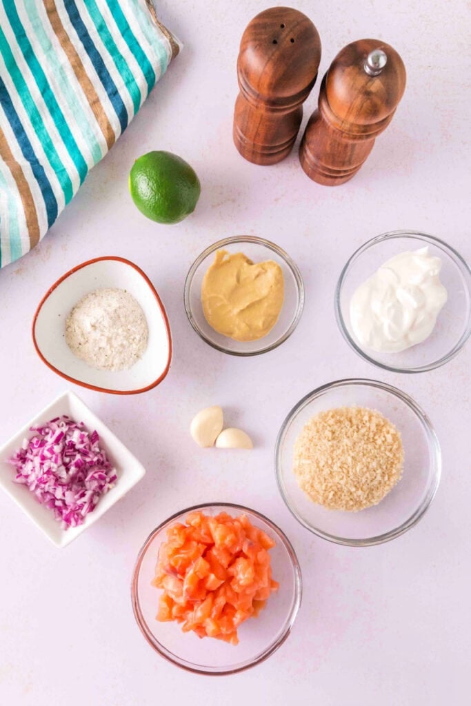 Overhead view of ingredients for salmon burger, including salmon, panko, onion, garlic, mustard, sour cream, and lime