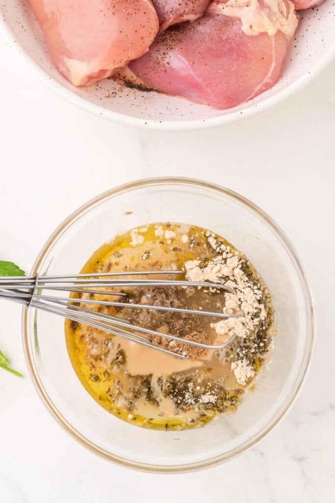 Whisk mixing together tahini, oil, lemon juice, and spices to create the marinade.