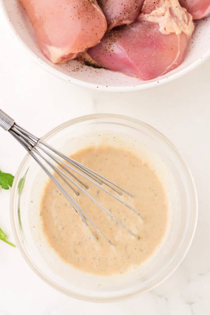 Smooth and creamy tahini chicken marinade fully mixed in a clear glass bowl.