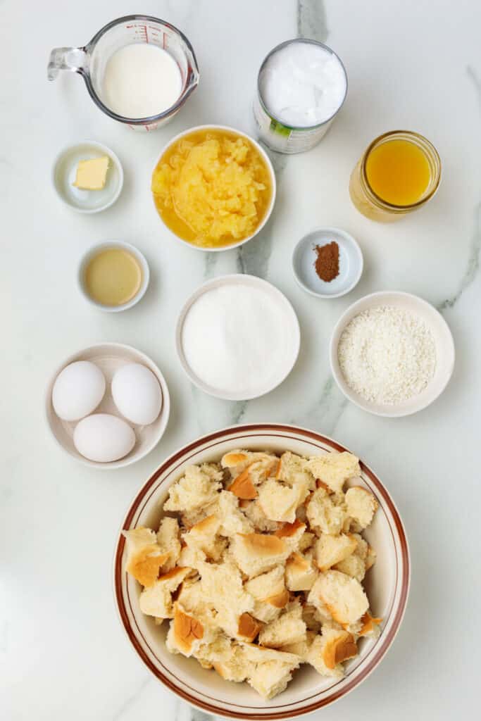 Overhead shot of measured ingredients for bread pudding on a white marble surface