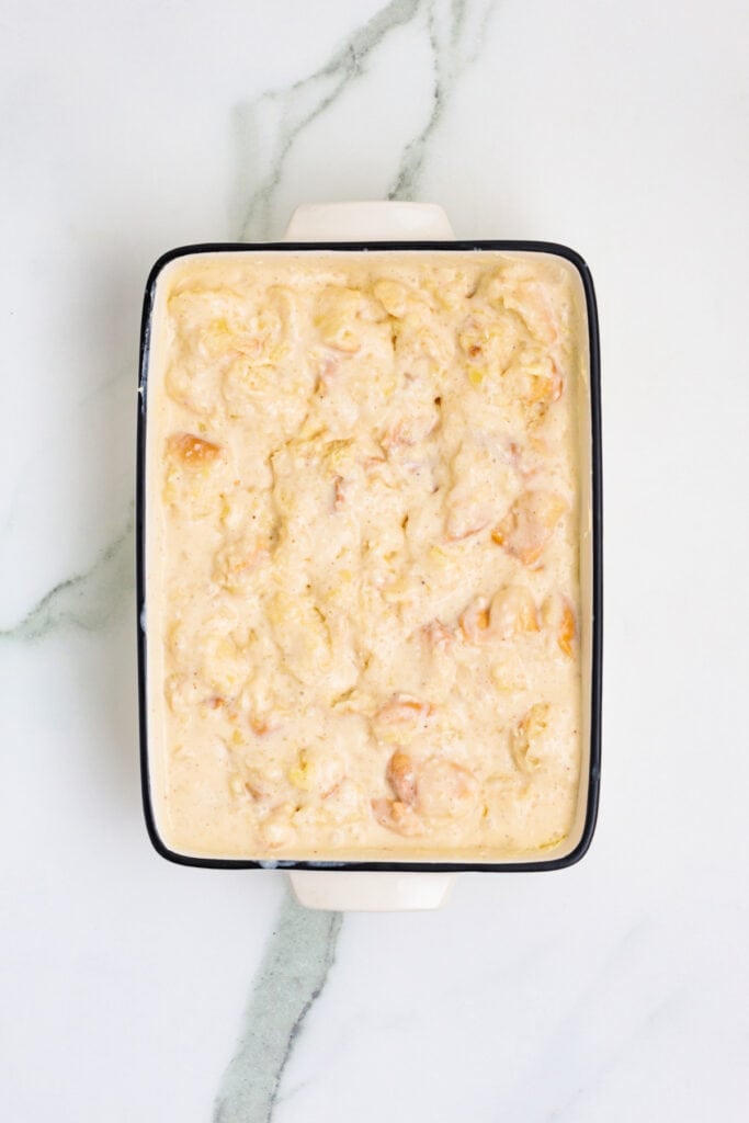 Custard-soaked bread pudding in a white baking dish before baking